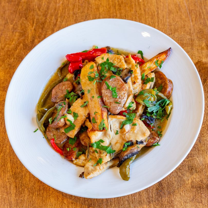 San Vito's chicken, sausage, peppers, and mushrooms in sauce, garnished with parsley.