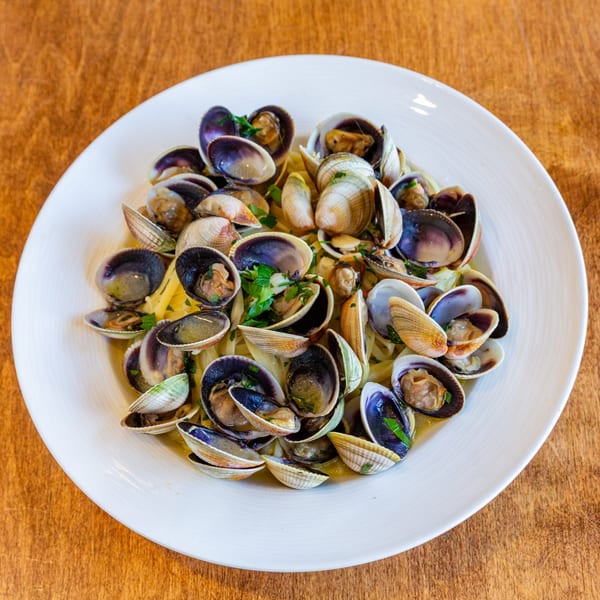 A white plate filled with linguine and clams, garnished with fresh parsley.