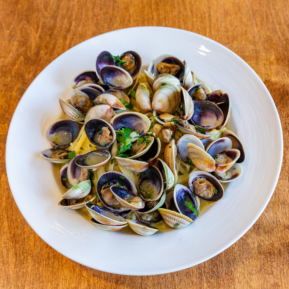 A white plate filled with linguine and clams, garnished with fresh parsley.